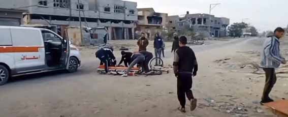 Rescue workers in Gaza attempt to pull a dead or wounded body from the street following an Israeli airstrike, highlighting the civilian toll of the ongoing conflict.