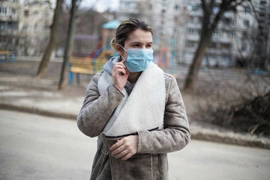 A woman wearing a protective mask on the street to guard against the HMPV virus, highlighting health precautions in public spaces