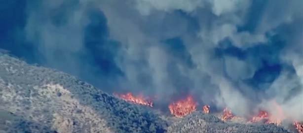 Hughes Fire in Southern California, showing intense flames and smoke, with residents evacuating due to severe wildfire danger.