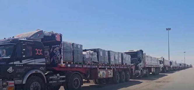 Aid trucks waiting at the Gaza border due to restrictions, highlighting the humanitarian crisis and supply blockade.