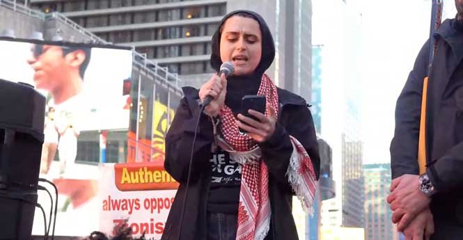 Female protester passionately gives a slogan on stage at a New York rally for Free Palestine.