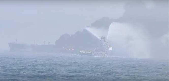 Firefighters battling a ship fire following a collision between an oil tanker and cargo ship at sea.